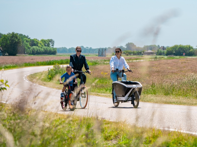 Een licht groene fiets geparkeerd op de stoep leunend tegen een stenen muur.