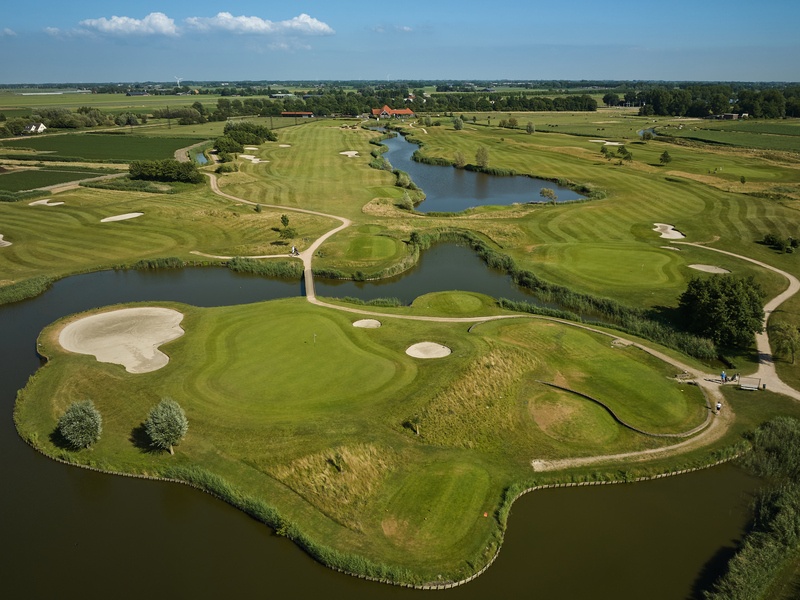 Golfbal naast een hole op een groene golfbaan